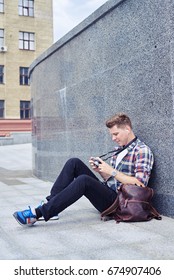 Side view of candid boy looking at photos in camera while listening to music. Wearing casual clothes 