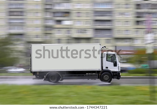 Side view of a cargo\
delivery truck blurred with an copy space on a blurred background\
in traffic