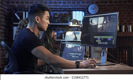 Side view of casual confident Korean man working on computer with video editing and color correction