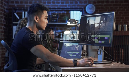 Side view of casual confident Korean man working on computer with video editing and color correction