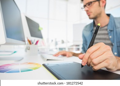 Side view of a casual male photo editor using graphics tablet in a bright office - Powered by Shutterstock