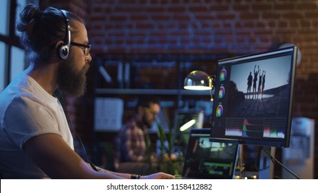 Side view of casual man in headphones working on computer and editing video with color correction - Shutterstock ID 1158412882