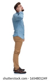 Side View Of A Casual Man Pointing To His Head And Looking Up, Standing On White Studio Background