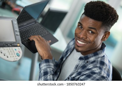 side view of casual man using laptop while checking printer