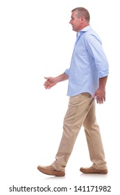 Side View Of A Casual Senior Man Walking And Looking Forward. Isolated On White Background