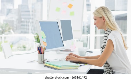 Side View Of A Casual Young Woman Using Computer In A Bright Office