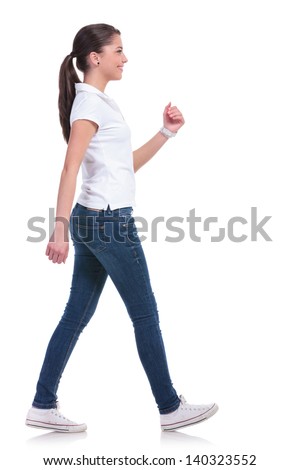 side view of a casual young woman walking away from the camera and smiling. isolated on white background