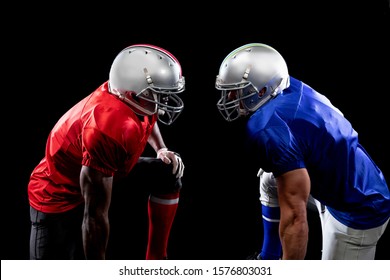 Side view of a Caucasian and an African American male American football player wearing helmets and their opposing team colours, standing opposite staring at each other - Powered by Shutterstock