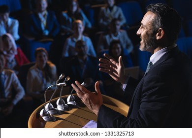 Side view of Caucasian businessman standing and giving presentation in the auditorium  - Powered by Shutterstock