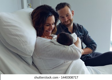 Side View Of Caucasian Couple Holding Their Newborn Baby In The Ward At Hospital