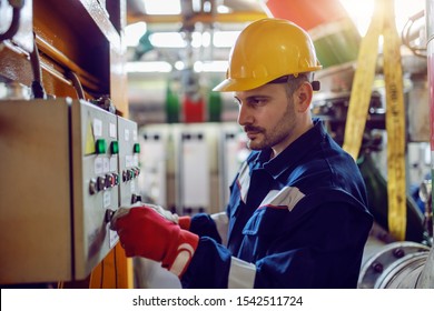 Side View Of Caucasian Energy Plant Worker In Working Clothes And With Helmet On Head Turning On Switch.