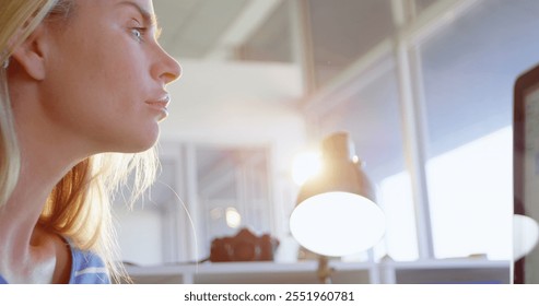 Side view of Caucasian female fashion designer using graphic tablet at desk in office. She is looking at computer 4k - Powered by Shutterstock