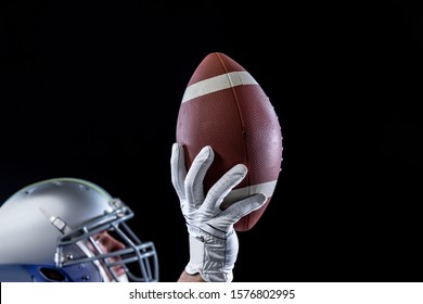 Side View Of A Caucasian Male American Football Playing Wearing A Helmet Looking Up And Holding A Football In One Gloved Hand