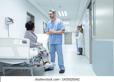 Side View Of Caucasian Male Doctor Interacting With Disabled Female Patient In The Corridor At Hospital