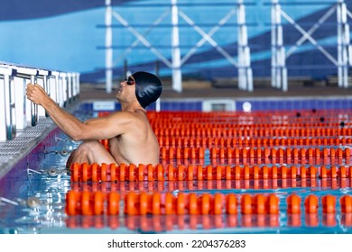 Side View Of Caucasian Male Swimmer At Swimming Pool, In Water Holding Onto S Starting Block, Starting A Backstroke Race