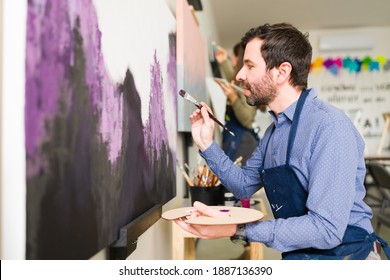 Side View Of A Caucasian Man In His 30s Doing An Abstract Painting On A Large Canvas For His Art Class For Adults 