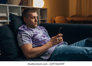 Side view of a Caucasian man using his mobile phone at home.