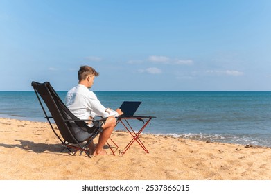 Side view of Caucasian man using laptop while sitting in sun lounger on beach on sunny day. Guy in white shirt working on laptop at sea, freelancer in world time - Powered by Shutterstock