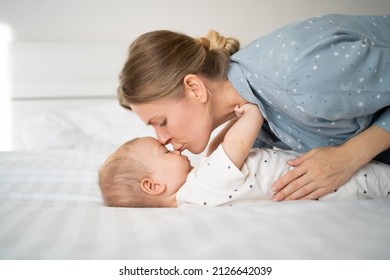 Side View Of A Caucasian Mother Lying With Her Newborn Baby On The Bed. Close-up Of A Baby With Mother. Woman And Charming Toodler On Bed