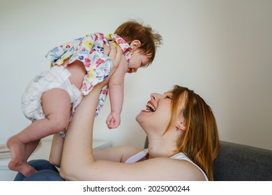 Side View Caucasian Woman Mother Holding Her Small Baby Girl Four Months Old In The Air Lifting Up And Swinging While Smiling Having Fun Parenting Leisure Motherhood Concept