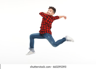 Side view of cheerful boy in casual clothing in moment of jump on white background.  - Shutterstock ID 663295393