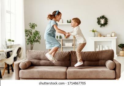 Side view of cheerful boy and girl holding hands and jumping on couch while having fun at home together
 - Powered by Shutterstock