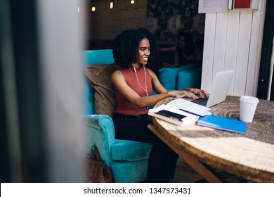 Side View Of Cheerful Female Blogger Enjoying Messaging With Followers From Website While Listening Music Playlist With High Volume, Happy Woman In Headphones Communicating Via Laptop Application