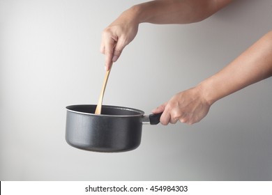 Side View Of Chef  Hand Holding A Cooking Pot With Wooden Spade. Cooking Action Concept