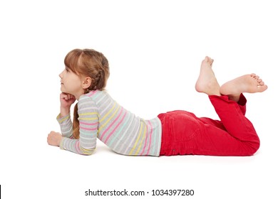 Side view of a child girl lying on front on the floor with crossed legs looking forward, over white background