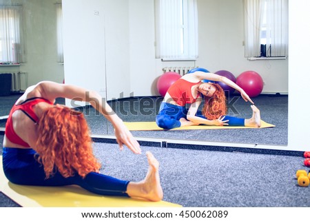 Side view of class stretching on mats at yoga class in fitness studio