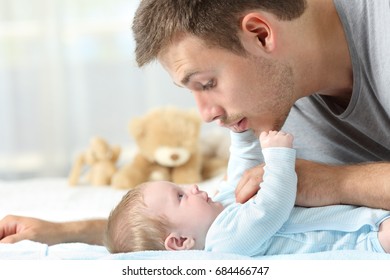 Side View Close Up Of A Baby And Father Playing Together On A Bed