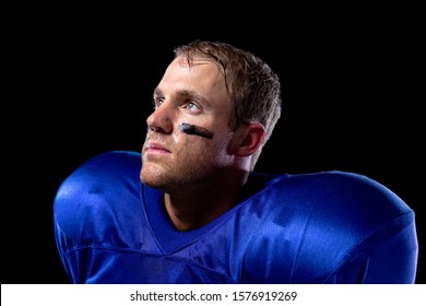 Side View Close Up Of A Caucasian Male American Football Player Wearing A Team Uniform With Shoulder Pads And Lines Of Eye Black Under His Eyes, Looking Up