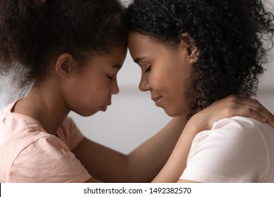 Side view close up faces of african mother and daughter touches foreheads moment of tenderness and caress. Concept of ask forgiveness or show gratitude for adoption to new mom, family is love concept - Powered by Shutterstock