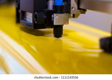 Side view and close up of a plotter that is used in industrial design cutting through yellow foil 