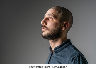 Side View Close Up Portrait Of Adult Caucasian Man With Beard And Short Hair Looking Up Thoughtful With Copy Space - Studio Shot