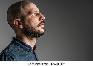 Side View Close Up Portrait Of Adult Caucasian Man With Beard And Short Hair Looking Up Thoughtful With Copy Space - Studio Shot