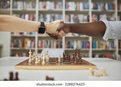 Side view close up of two chess players shaking hands over chess board after match
