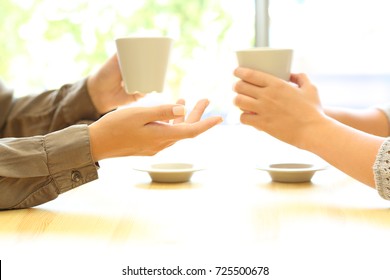 Side view close up of two women hands talking in a bar or house holding coffee cups