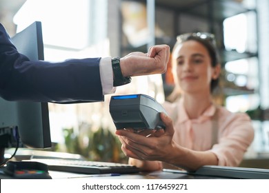 Side view close up of unrecognizable businessman paying via smartwatch at counter in shop, copy space - Powered by Shutterstock