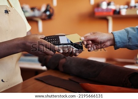 Side view close up of unrecognizable young woman holding banking terminal with client paying by credit card