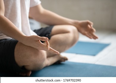 Side View Close Up Young Male Sitting In Lotus Position With Mudra Gesture, Meditating After Finishing Intensive Yoga Class Or Starting Practicing Breathing Exercises Before Training Start In Studio.