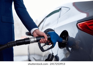 Side view closeup of businessman refueling gas tank of luxury car in petrol station - Powered by Shutterstock