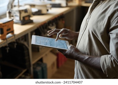 Side view closeup of carpenter holding digital tablet in workshop with woodworking plans on screen - Powered by Shutterstock