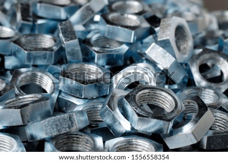 Side view close-up chrome metal nuts in the shape of honeycombs lie next to each other forming an area. The concept of fasteners and construction. Repair and parts concept
