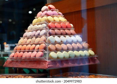 side view closeup of colorful assorted macarons cakes arranged in pyramid shape in candy store window