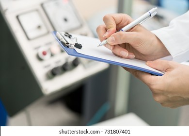 Side view close-up of the hands of a female engineer or inspector, ready for writing a technical report about the manufacturing process in a contemporary factory - Shutterstock ID 731807401