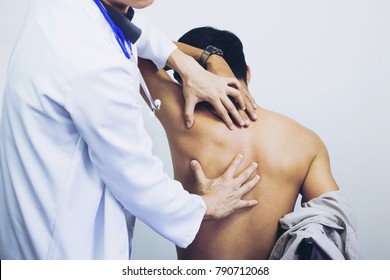 Side view close-up of a male physiotherapist examining mans back in the medical office. Doctor and patient man with a back pain. - Powered by Shutterstock