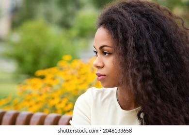 Side View Closeup Portrait Of Young African American Woman With Loose Wavy Curls African American Hair Outdoors On Nature Background. Attractive Mixed Race Dark-skinned Brunette Girl. Soft Focus.