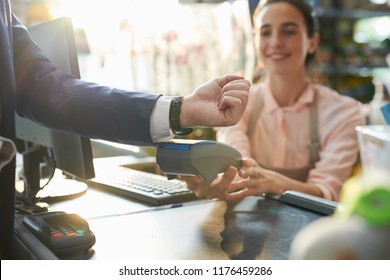 Side view closeup of unrecognizable businessman paying via smartwatch at counter in shop, copy space - Powered by Shutterstock