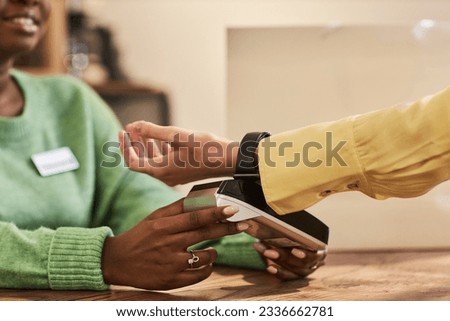 Side view closeup of unrecognizable young woman paying via smartwatch in store, copy space
